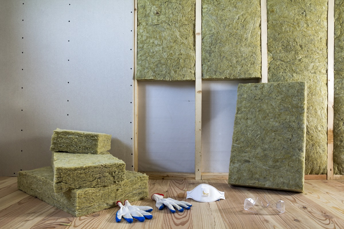 Изоляционные плиты на полу, строительные перчатки и маска.