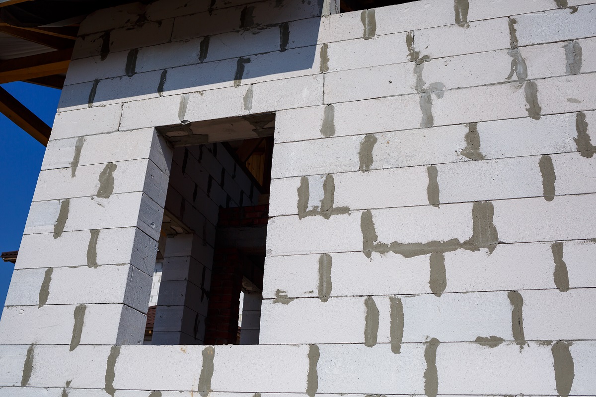 Стена из газобетонных блоков с видимыми швами и отверстиями.