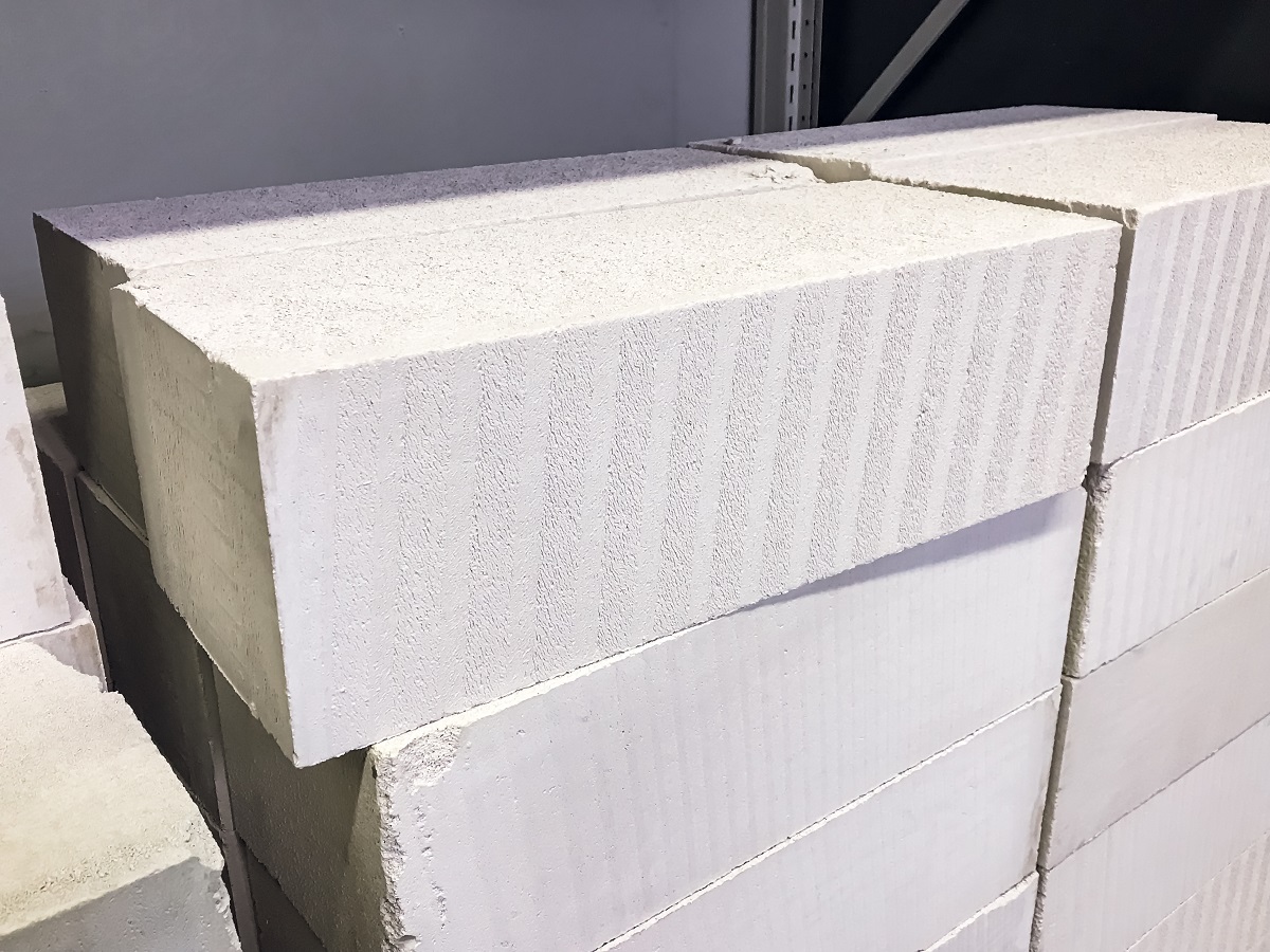 Стена из газобетонных блоков с видимыми швами и отверстиями.